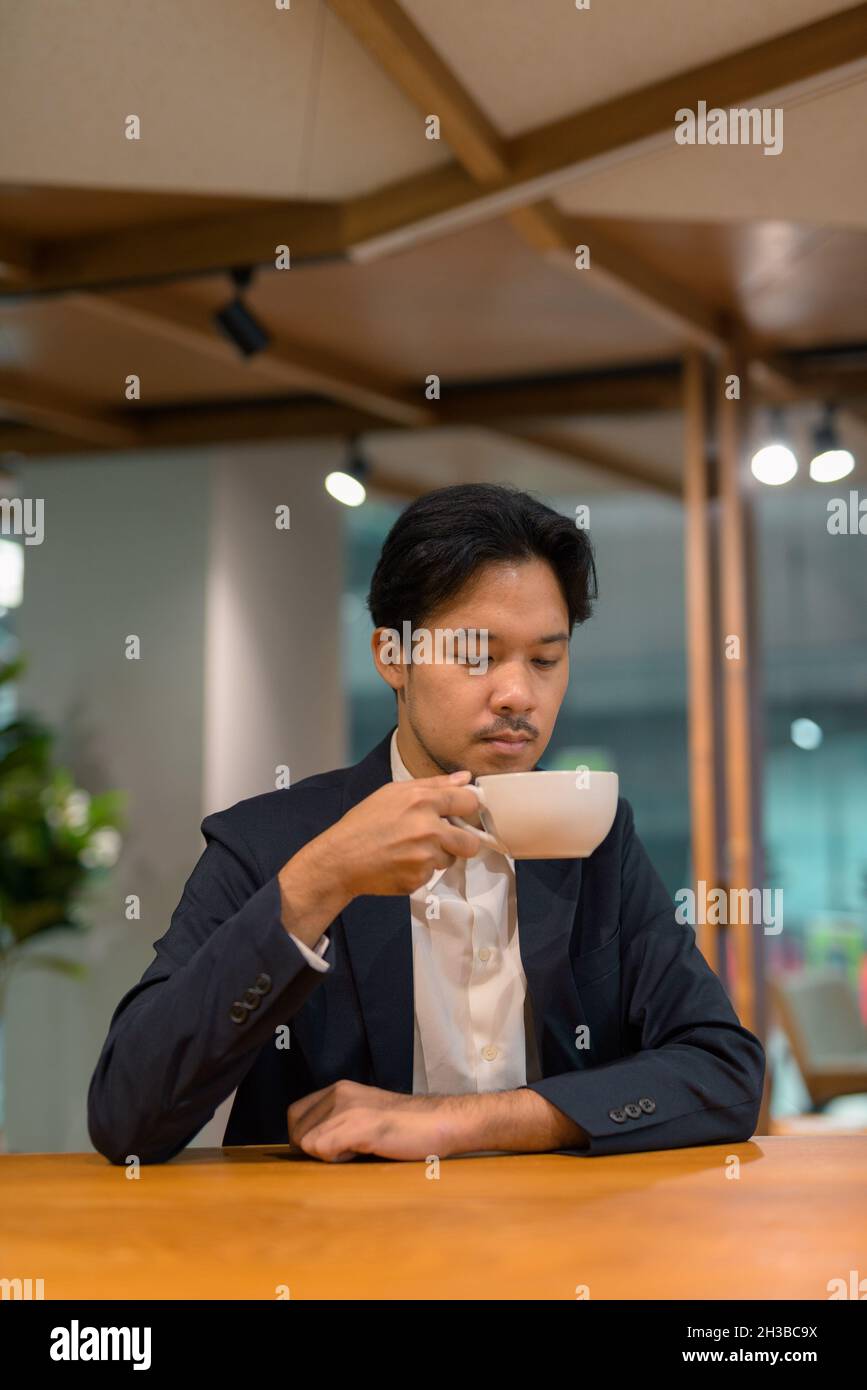 Portrait of Asian businessman sitting at restaurant and drinking coffee Stock Photo