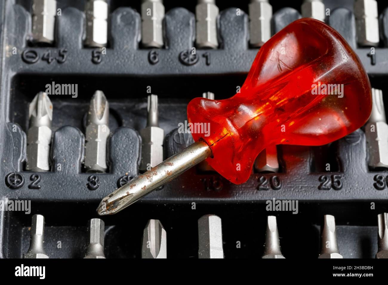 The screwdriver has a red handle and there are several bits Stock Photo