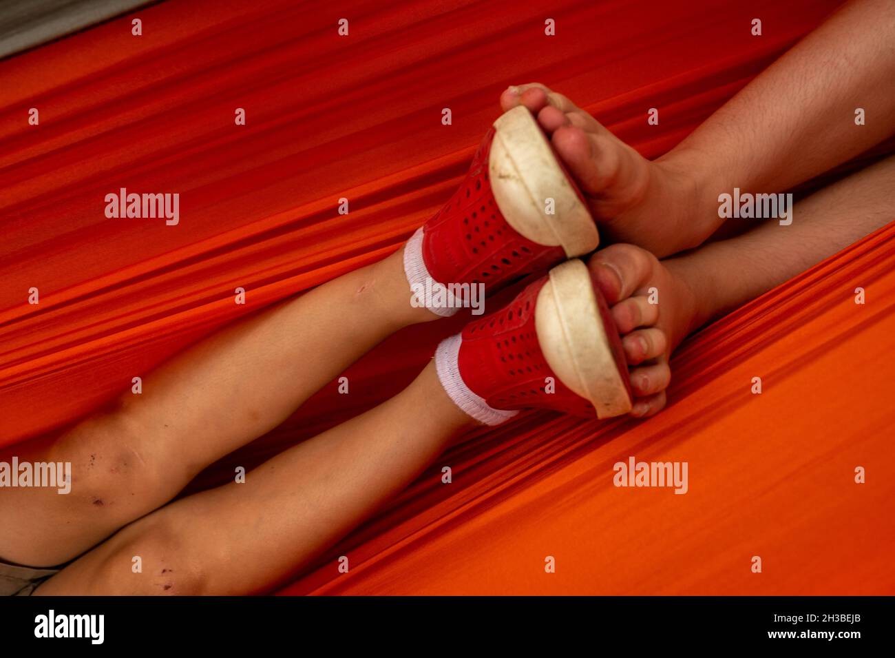 Sweet moment with two sets of kids' feet touching in a hammock Stock Photo