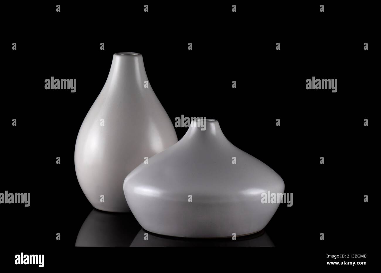 Two curvy white vases on black, with reflection. Stock Photo