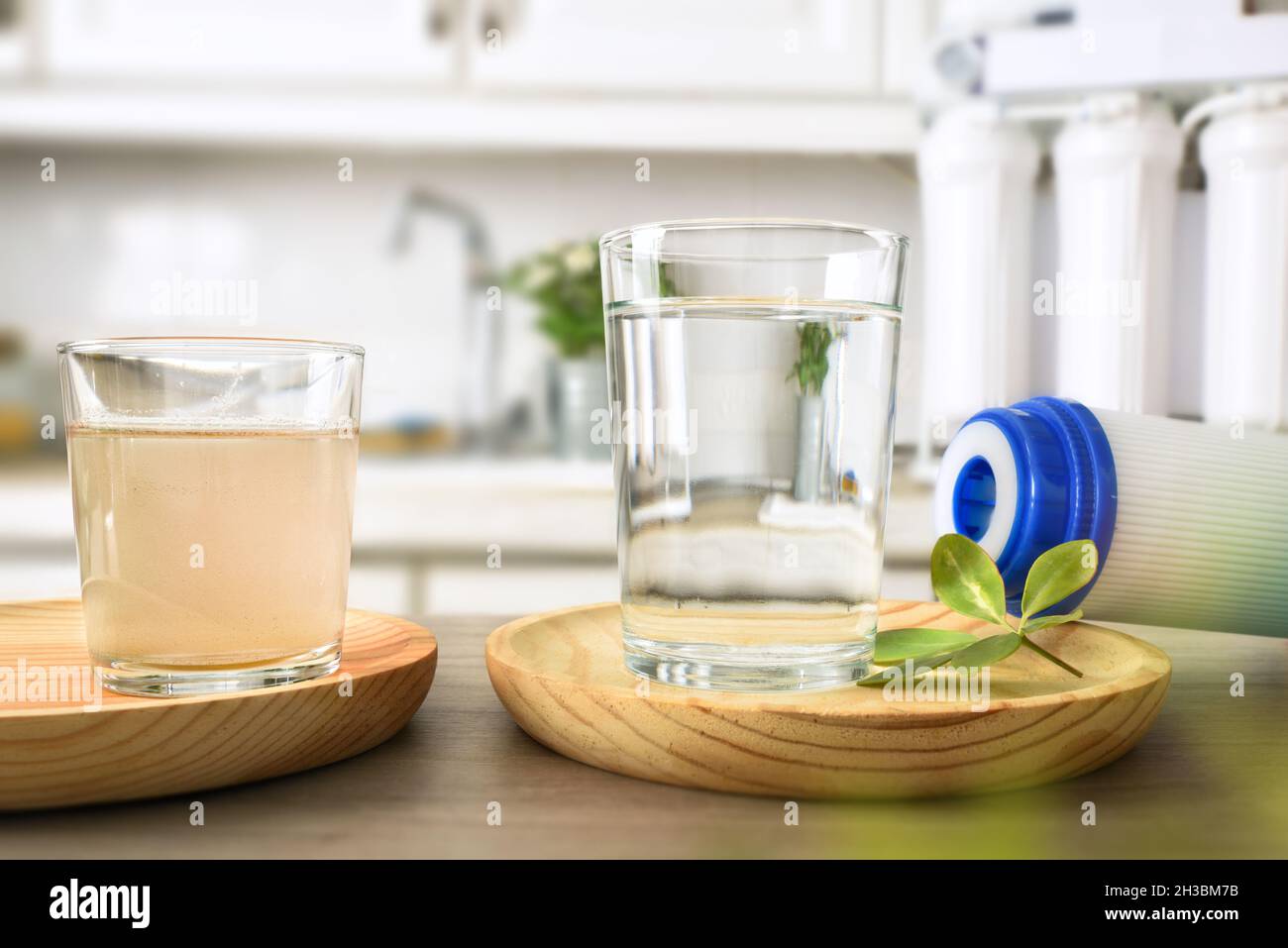 Comparison of dirty water and filtered by osmosis in glasses on a kitchen bench with filter and equipment in the background. Front view. Horizontal co Stock Photo