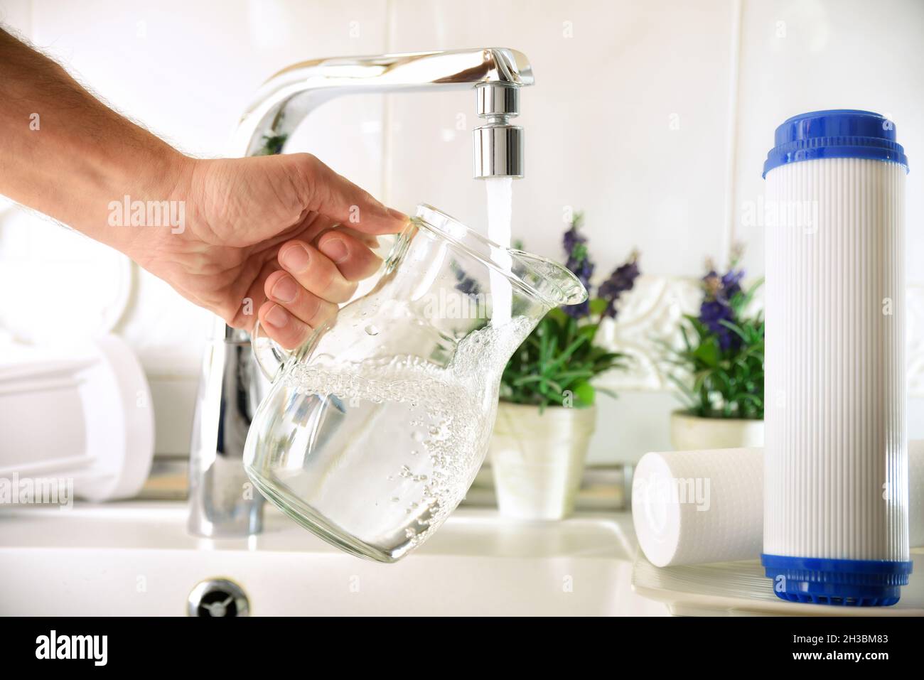 Man filling a glass jug from a tap of purified water with an osmosis