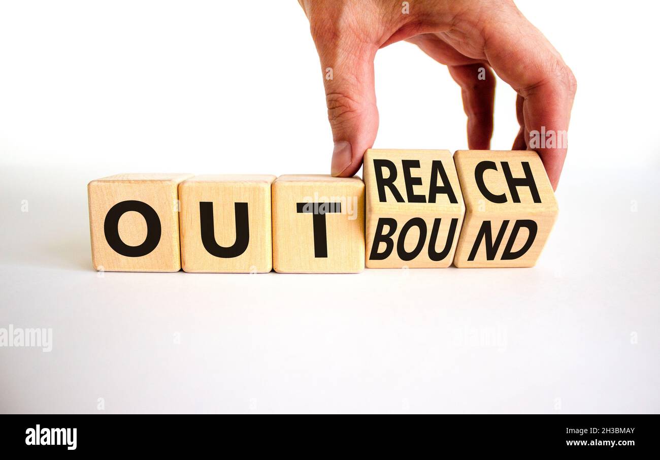 Outreach or outbound symbol. Businessman turns wooden cubes and changes the word 'outbound' to 'outreach'. Beautiful white table, white background. Bu Stock Photo