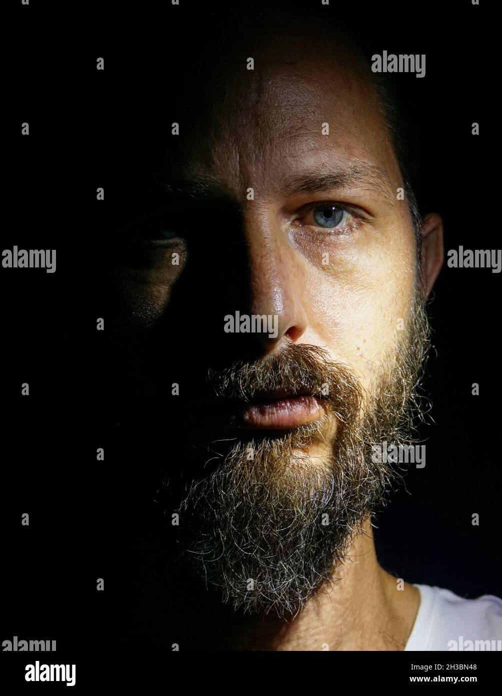 Man portrait. Close up. Face man portrait. lowkey black background. blue eyes. israeli model. beard mustach. serious. israel givaat avni. Stock Photo