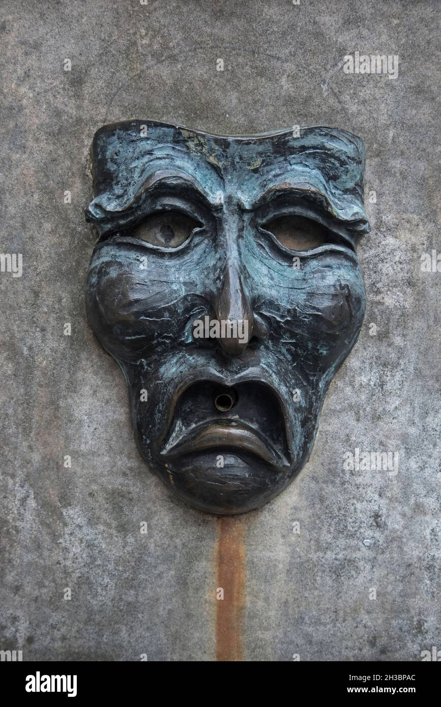 Bronze mask with a sad face on the wellhead outside the Edinburgh Fringe Office on The Royal Mile, Edinburgh, Scotland, UK. Stock Photo