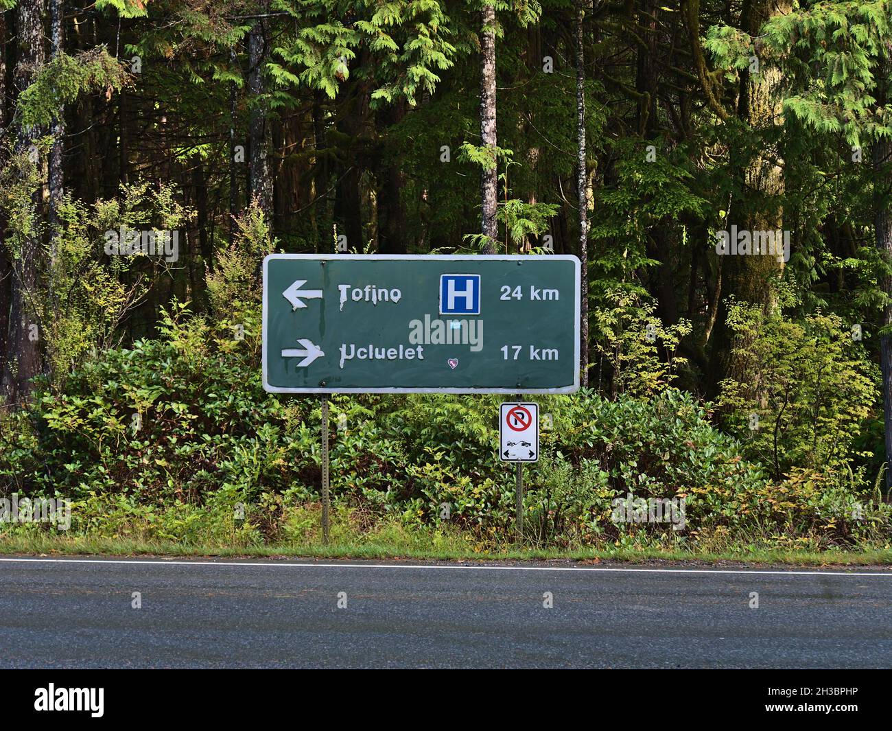 Front view of directional road sign near Rainforest Trail showing the directions and distance to Tofino and Ucluelet. Focus on sign. Stock Photo