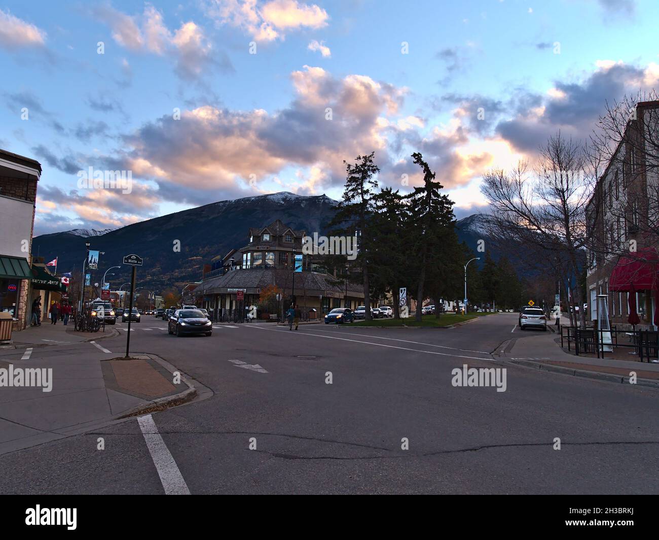 Beautiful view of Jasper downtown, located in the Canadian Rocky Mountains, in the evening light in autumn with car passing by and old buildings. Stock Photo