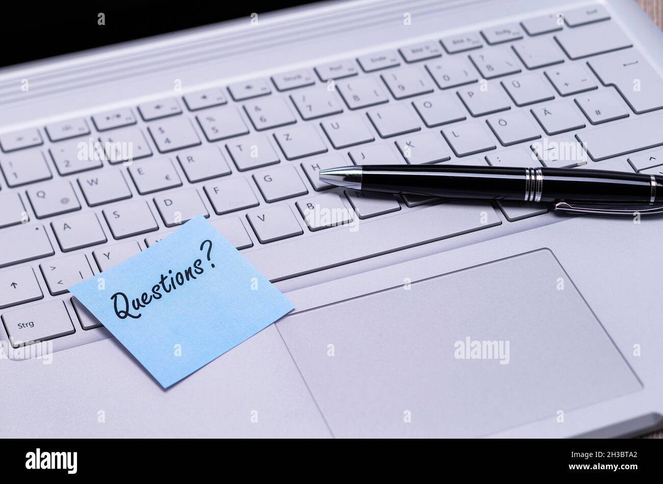 The photo shows a note with the text questions on a notebook computer Stock Photo