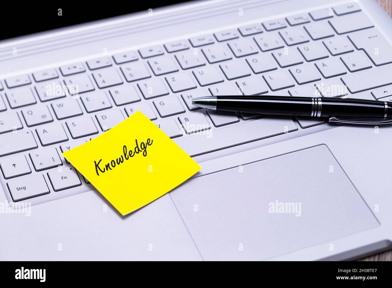 The photo shows a note with the text knowledge on a notebook computer Stock Photo