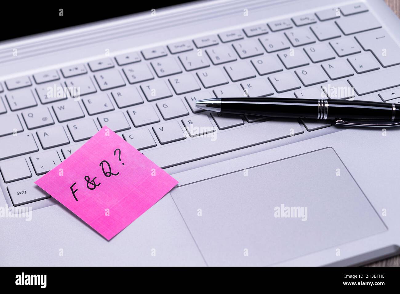 The photo shows a note with the text FAQ on a notebook computer Stock Photo