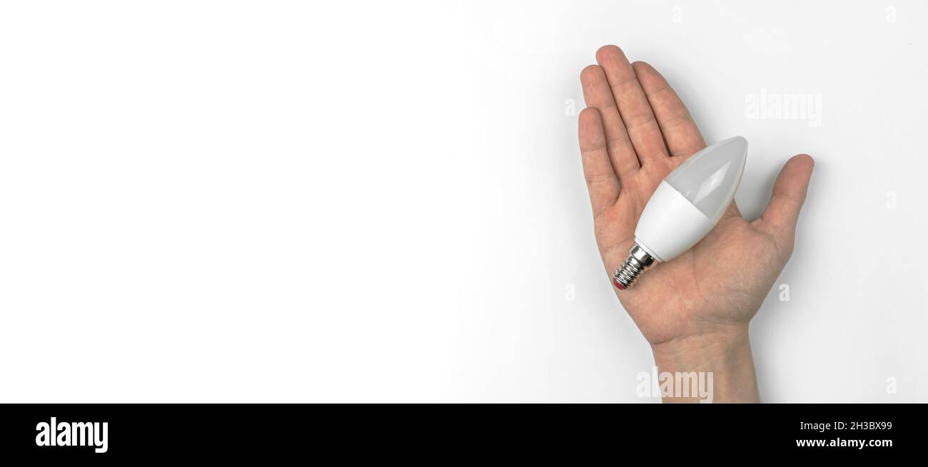 Hand with modern LED light bulb on a white table background with copy ...