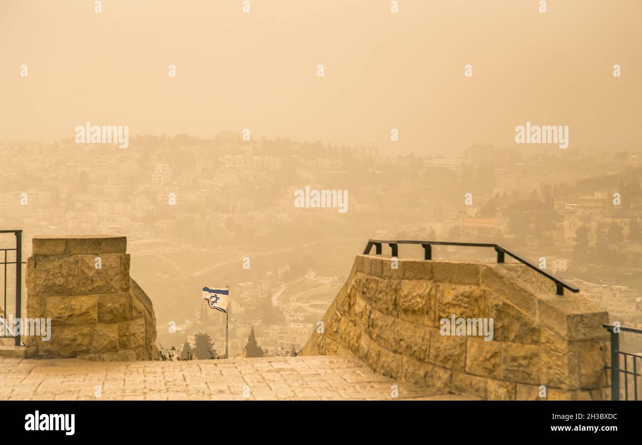 Sandstorm in center of downtown Jerusalem. View from Mount of Olives with Israel flag on the background. Extreme weather. Stock Photo
