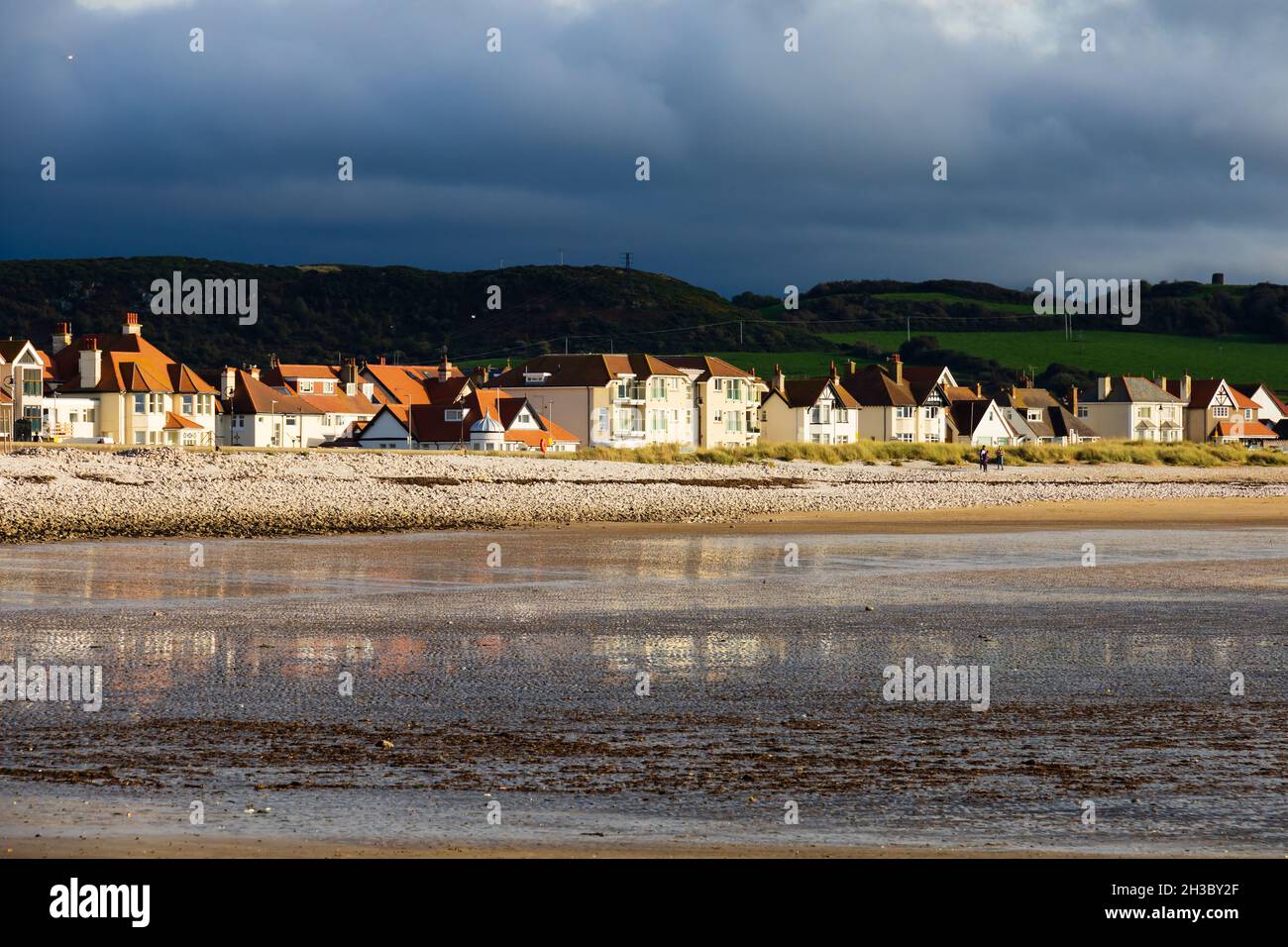 Houses on the shore at Llandudno, West Shore Beach, Clwyd, Wales. Dark, stormy clouds behind. Stock Photo