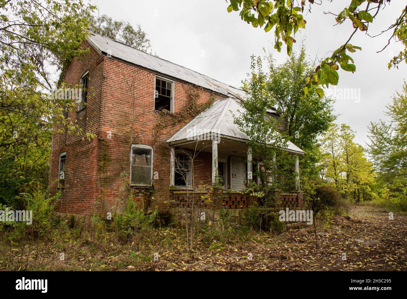 An abandoned brick house wit a hip roof over the porch in the midwest in the United States. Stock Photo