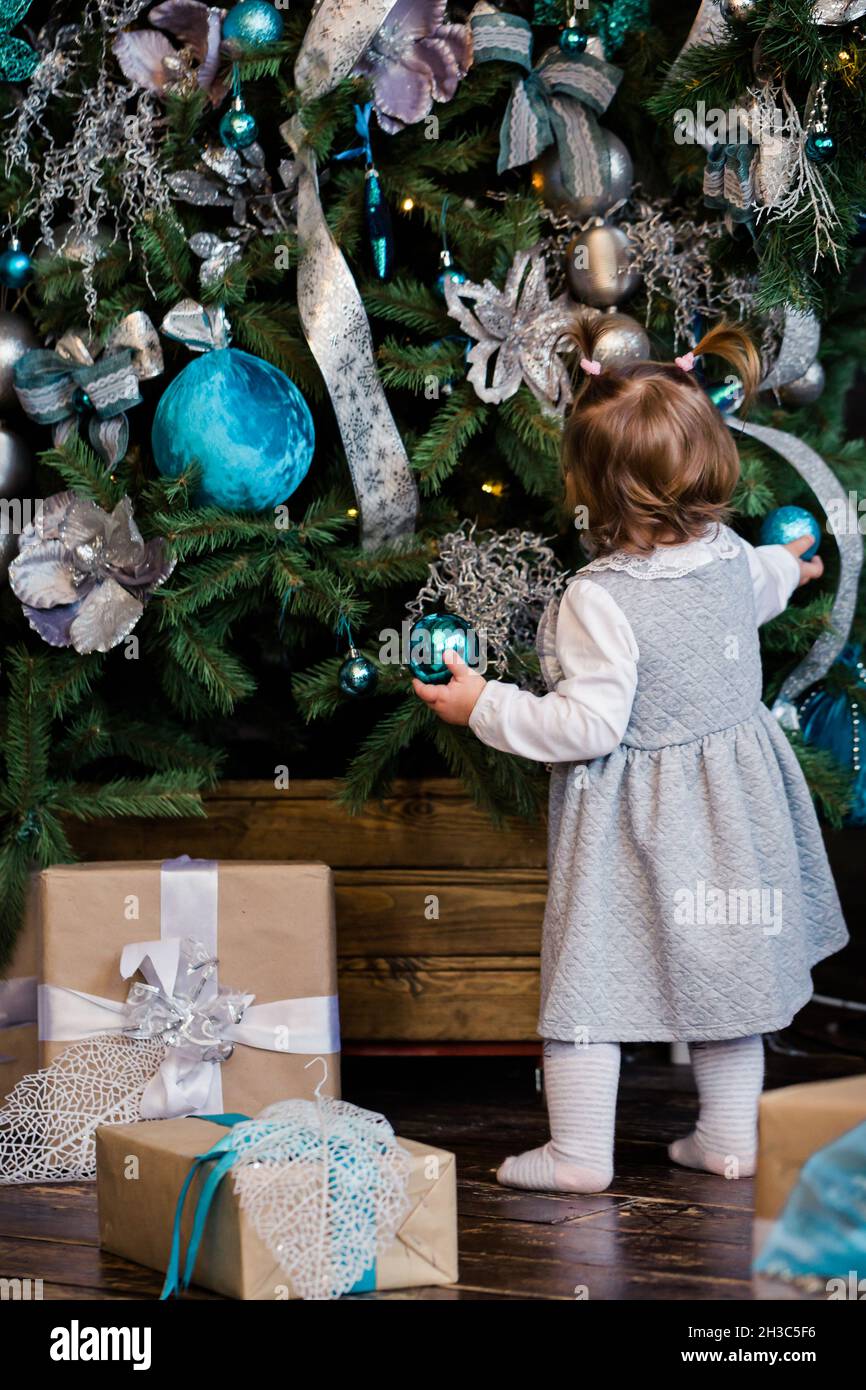 Little daugher decorate the Christmas tree at home. Family, x-mas, winter holidays and people concept. Family with kid celebrate winter holidays. Stock Photo