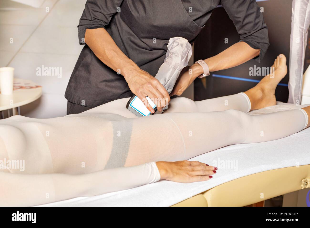 A professional massage therapist performs an electromagnetic massage of the patient's body muscles on a high-intensity simulator. Stock Photo