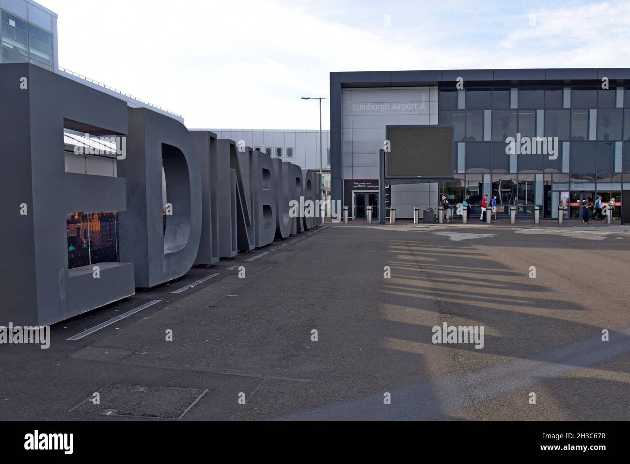 Passengers with luggage arriving at Edinburgh Airport, beside an