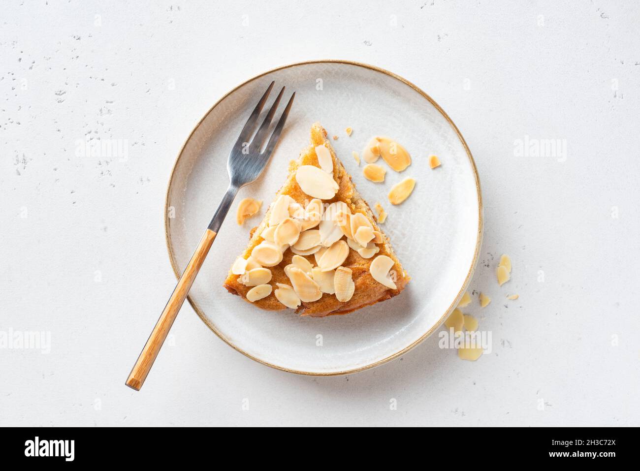 Slice of delicious almond cake on a plate, top view, grey stone background Stock Photo