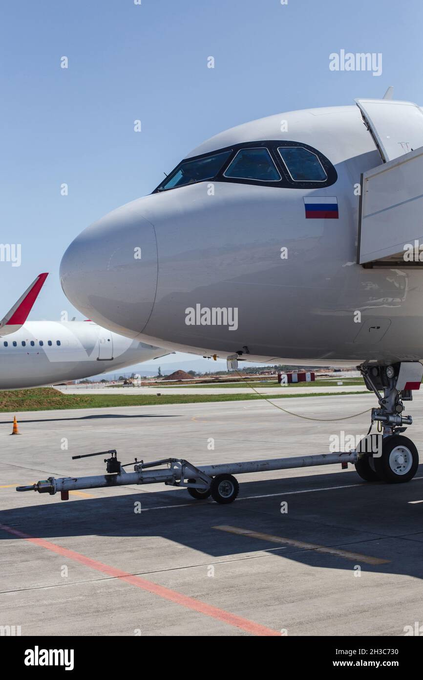 White airplane on runway at airport. Nose part. Modern aircraft on ground. Aviation Russian flag Stock Photo