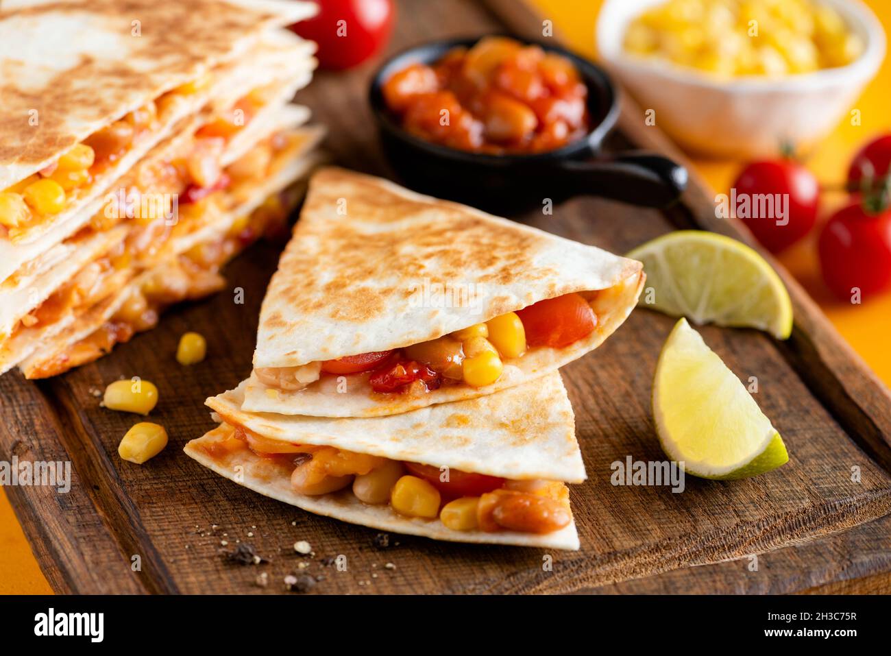 Vegetarian quesadilla with beans and tomatoes on wooden board, closeup view. Mexican cuisine food Stock Photo
