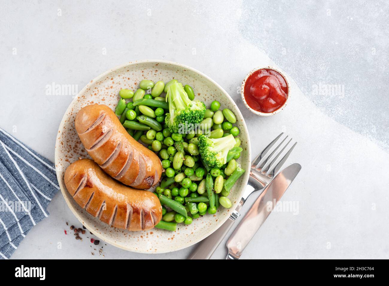 Low fat Turkey sausages served with green peas, broccoli and beans. Top view copy space for text Stock Photo