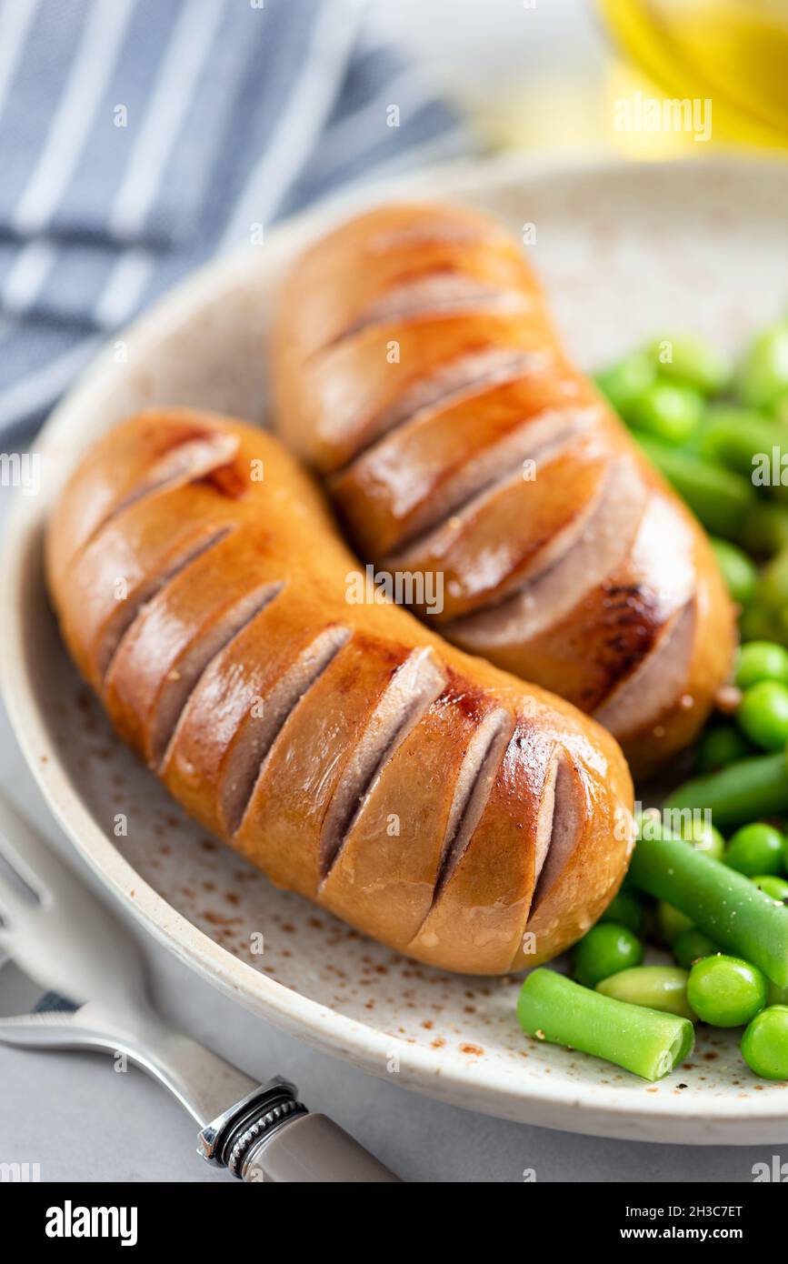 Grilled turkey sausages with green peas and broccoli. Balanced meal concept Stock Photo