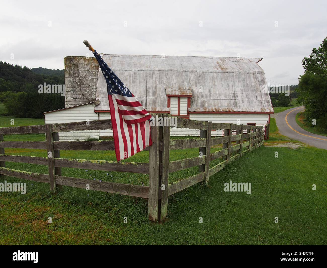 An American flag flies on a post-and-rail fence at an old barn in Virginia, USA, 2021 © Katharine Andriotis Stock Photo