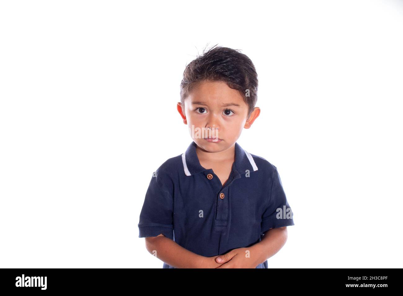 Little boy with look of sadness and regret, isolated on white background. Latin child afraid of being punished. Being reprimanded. Stock Photo