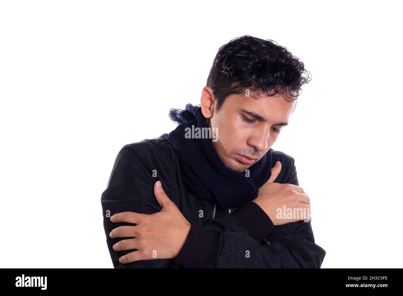 Man in very cold wearing a jacket and scarf, isolated on white background. Young adult can't stand so much cold. Stock Photo