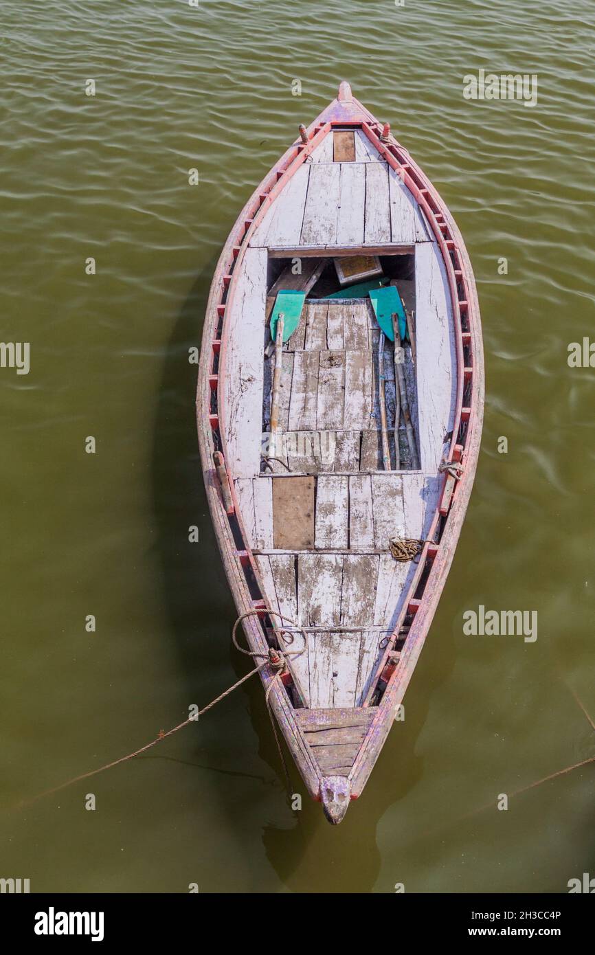 Small boat near Ghats riverfront steps leading to the banks of the River Ganges in Varanasi, India Stock Photo