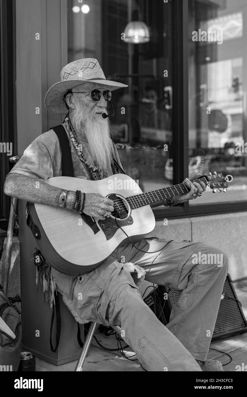 Local oldtimer playing music on his guitar for local passerby's in