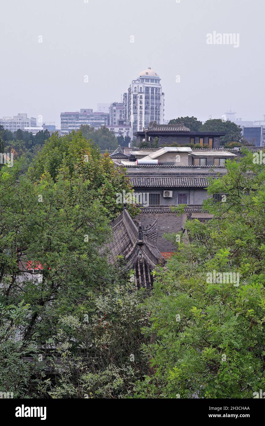 Multi inclined gabled roofs-old style houses-green trees-modern buildings background. Xi'an-China-1600 Stock Photo
