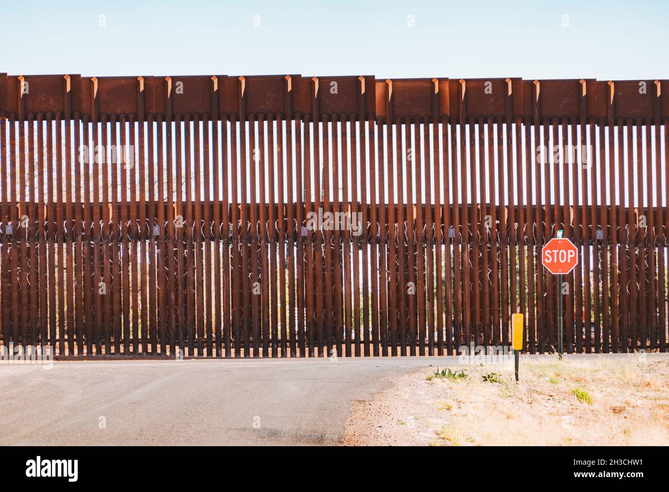 a stop sign in front of the steel US-Mexico border wall in the town of Naco, Arizona, United States Stock Photo