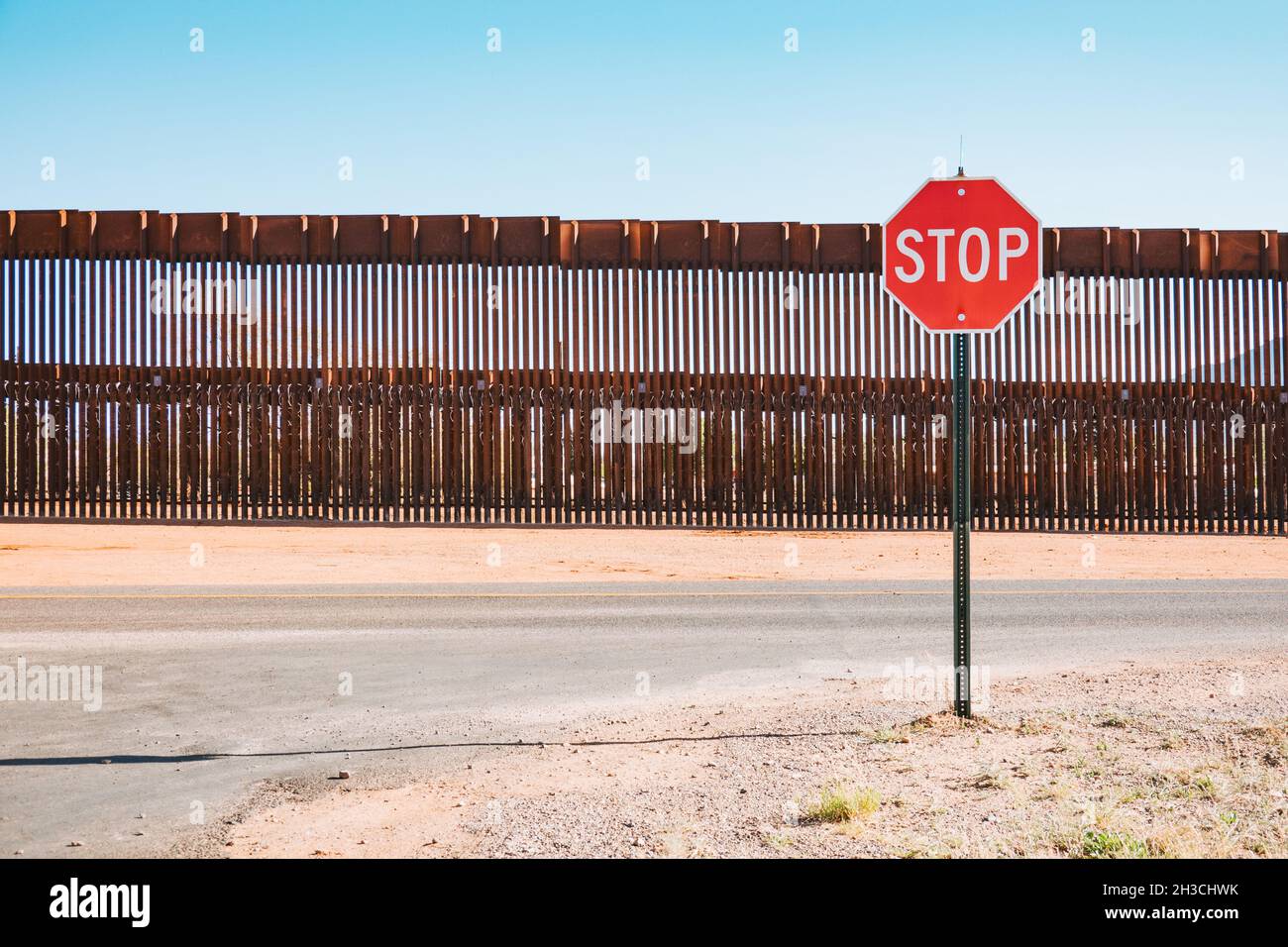 a stop sign in front of the steel US-Mexico border wall in the town of Naco, Arizona, United States Stock Photo