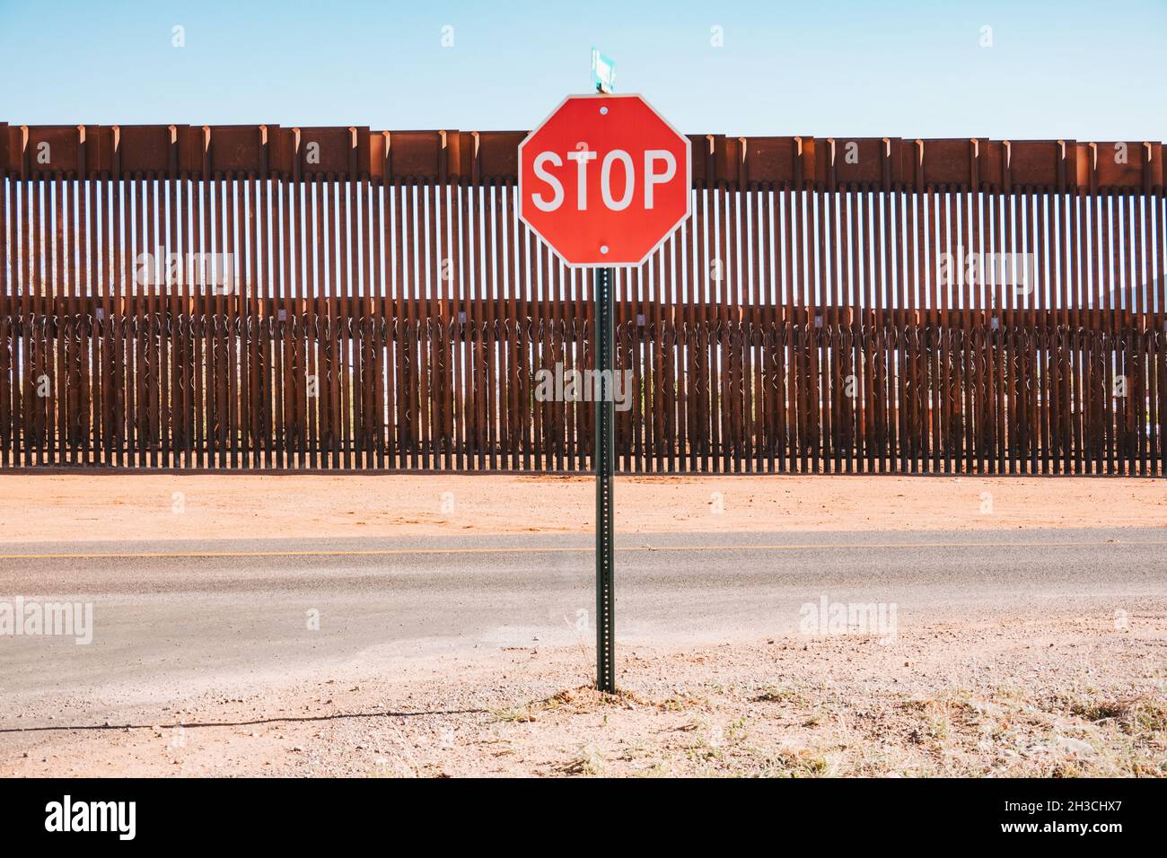 a stop sign in front of the steel US-Mexico border wall in the town of Naco, Arizona, United States Stock Photo