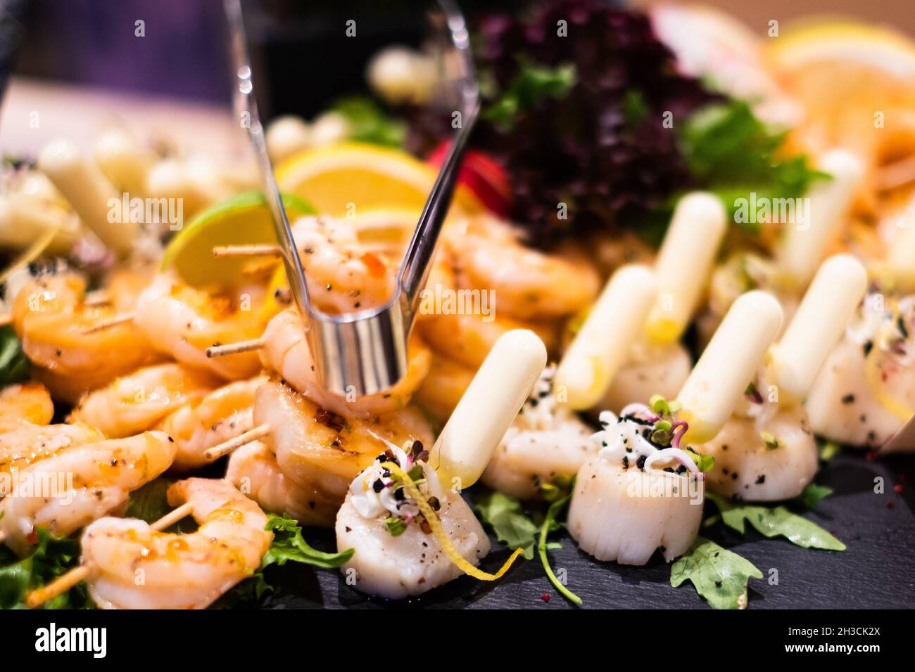 Grilled tiger prawns and baked scallops with lemon-saffron sauce. Delicious professional looking food and snacks served at catering event or party Stock Photo