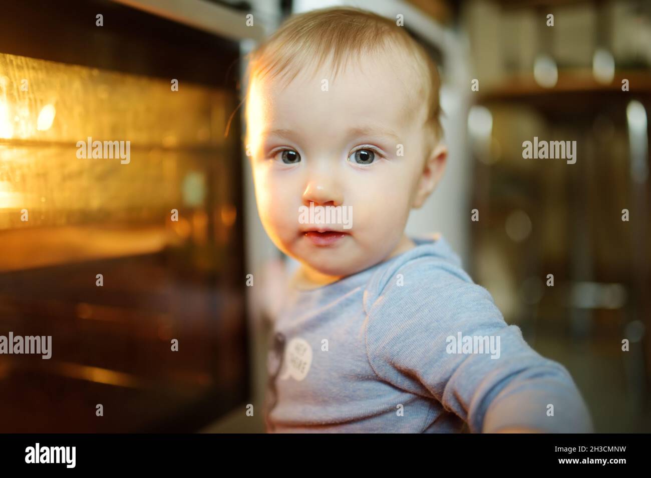 Little child playing with electric stove in the kitchen. Toddler boy