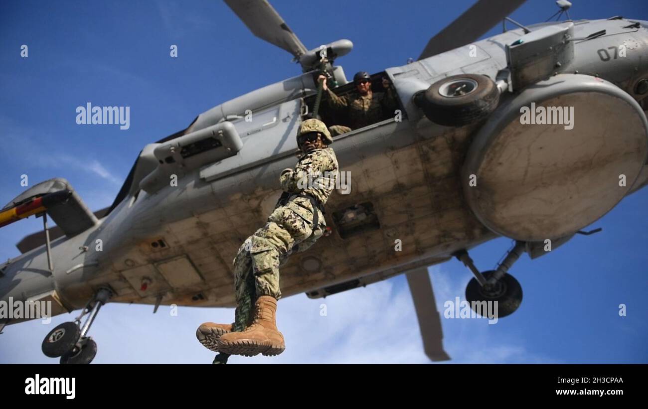 NAVAL STATION ROTA, Spain (Sept. 30, 2021) Utilitiesman Constructionman Tarique Daley, from Fort Lauderdale, Fla., assigned to Naval Mobile Construction Battalion 1, fast-ropes out of a Spanish SH-60B Seahawk helicopter during exercise Lisa Azul, Sept. 30, 2021. Lisa Azul is a joint nation exercise between the U.S. and Spanish expeditionary forces designed to strengthen capabilities and interoperability through information exchanges and combined operations. (U.S. Navy photo by Mass Communication Specialist 1st Class Caine Storino) Stock Photo