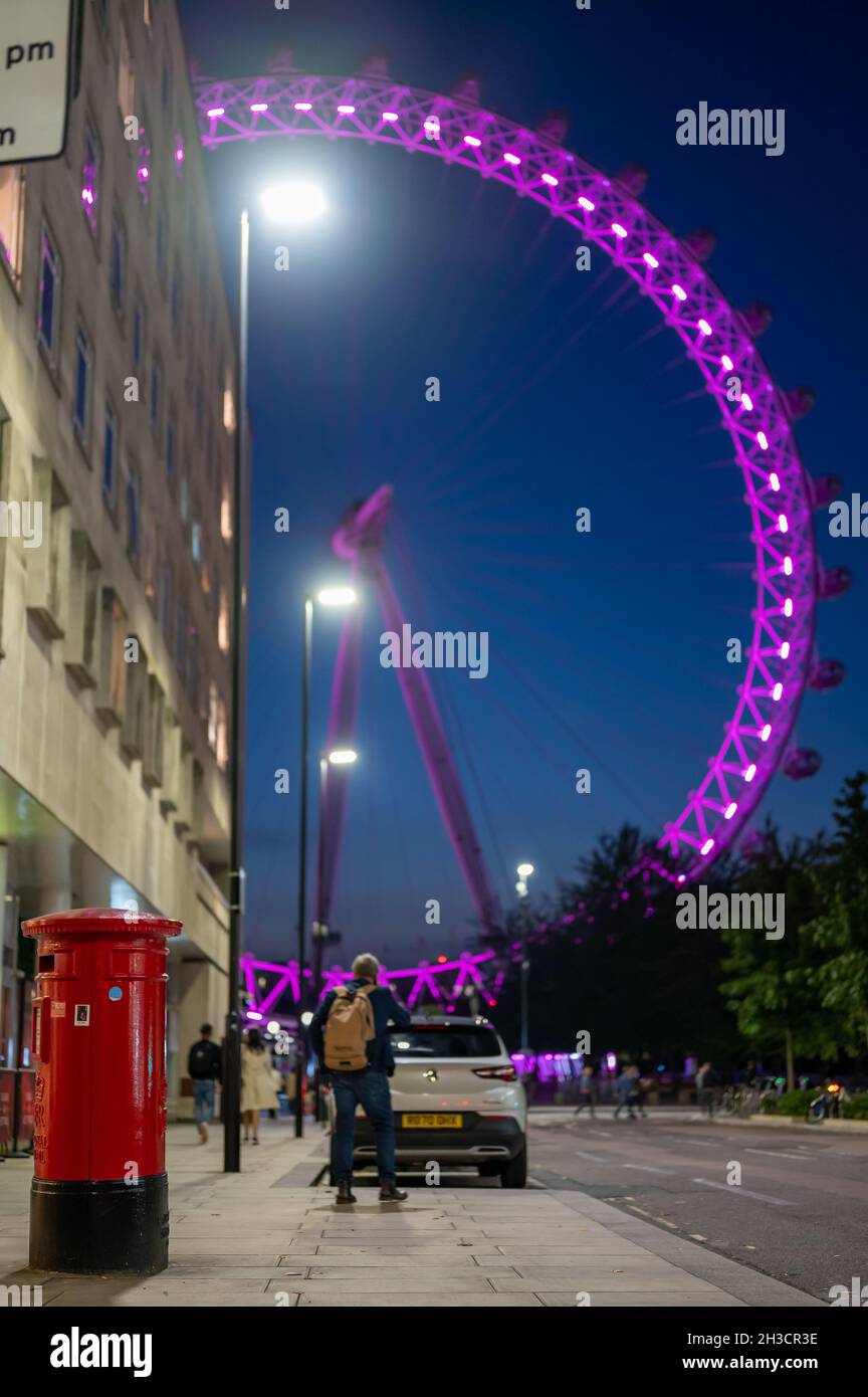 LONDON - SEPTEMBER 14, 2021: Red British Post Box next to County Hall Apartments with the London Eye lit up at night in the background Stock Photo