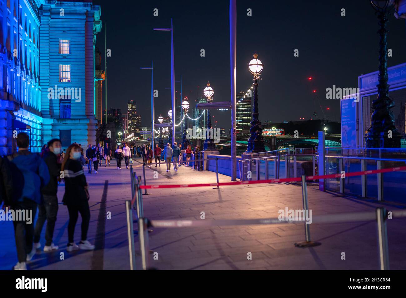 LONDON - SEPTEMBER 14, 2021: Colourfully lit night scene on The Queen's Walk, Southbank between The London Eye and County Hall Stock Photo