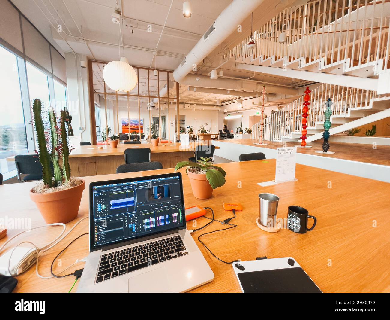 A laptop with video editing software on a table in a WeWork in Tempe, Arizona Stock Photo
