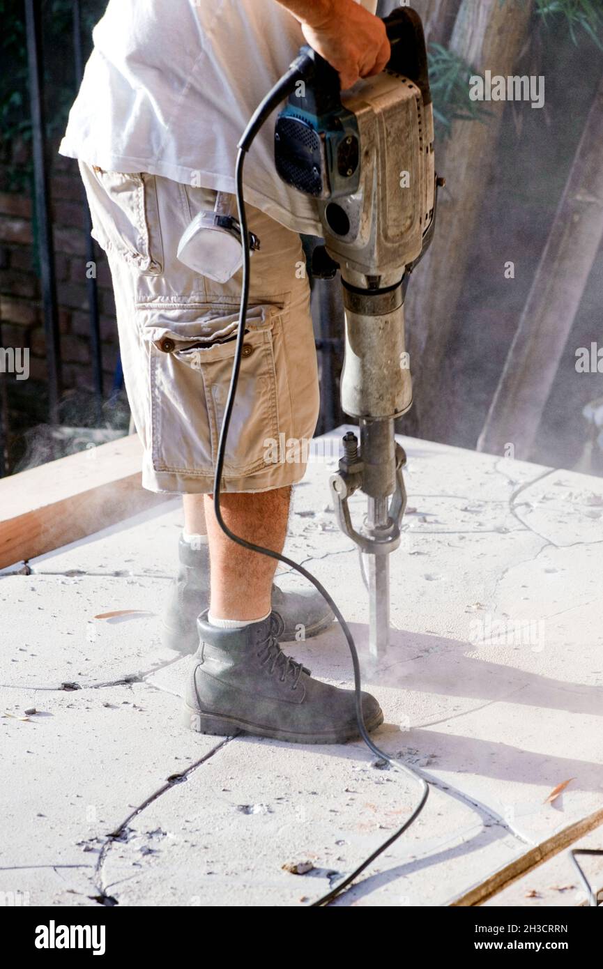 Construction worker using a jackhammer to demolish an old concrete slab