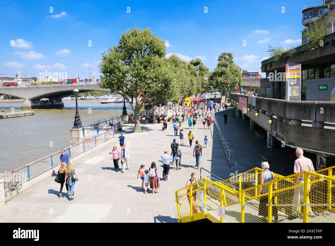 London's South Bank in summer.  People walking along Queen's Walk on Thames Path next to the Southbank Centre on a warm sunny day. London, England, UK Stock Photo