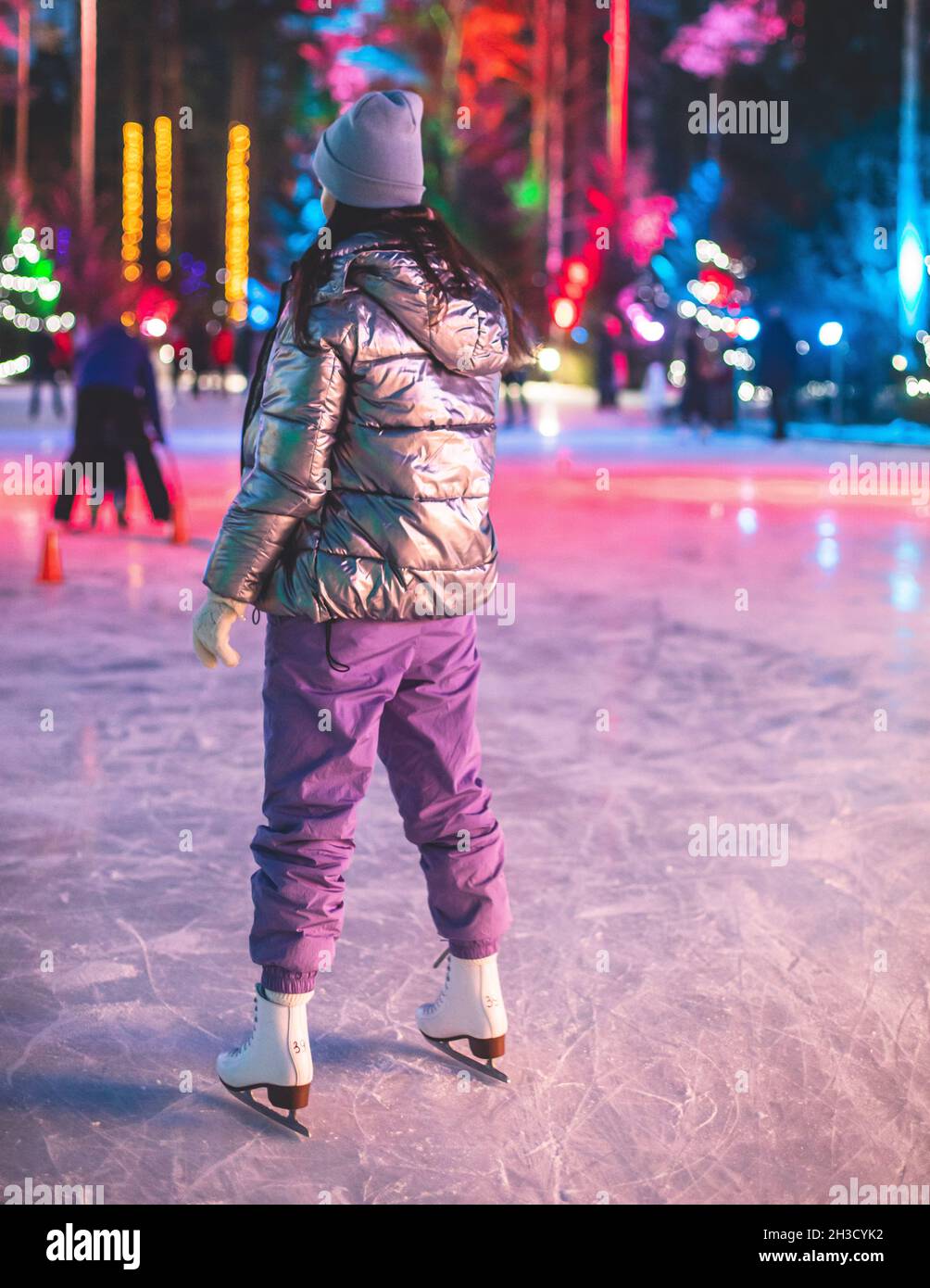 Girl ice skating on the ice rink arena with happy people around