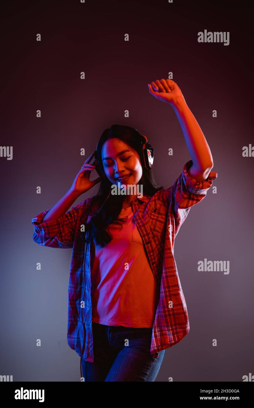 woman dancing while listening to music with headphones in dark room ...
