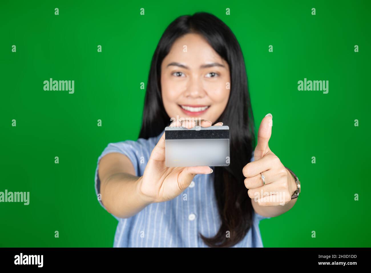 asian woman looking at camera while holding atm card with thumbs up
