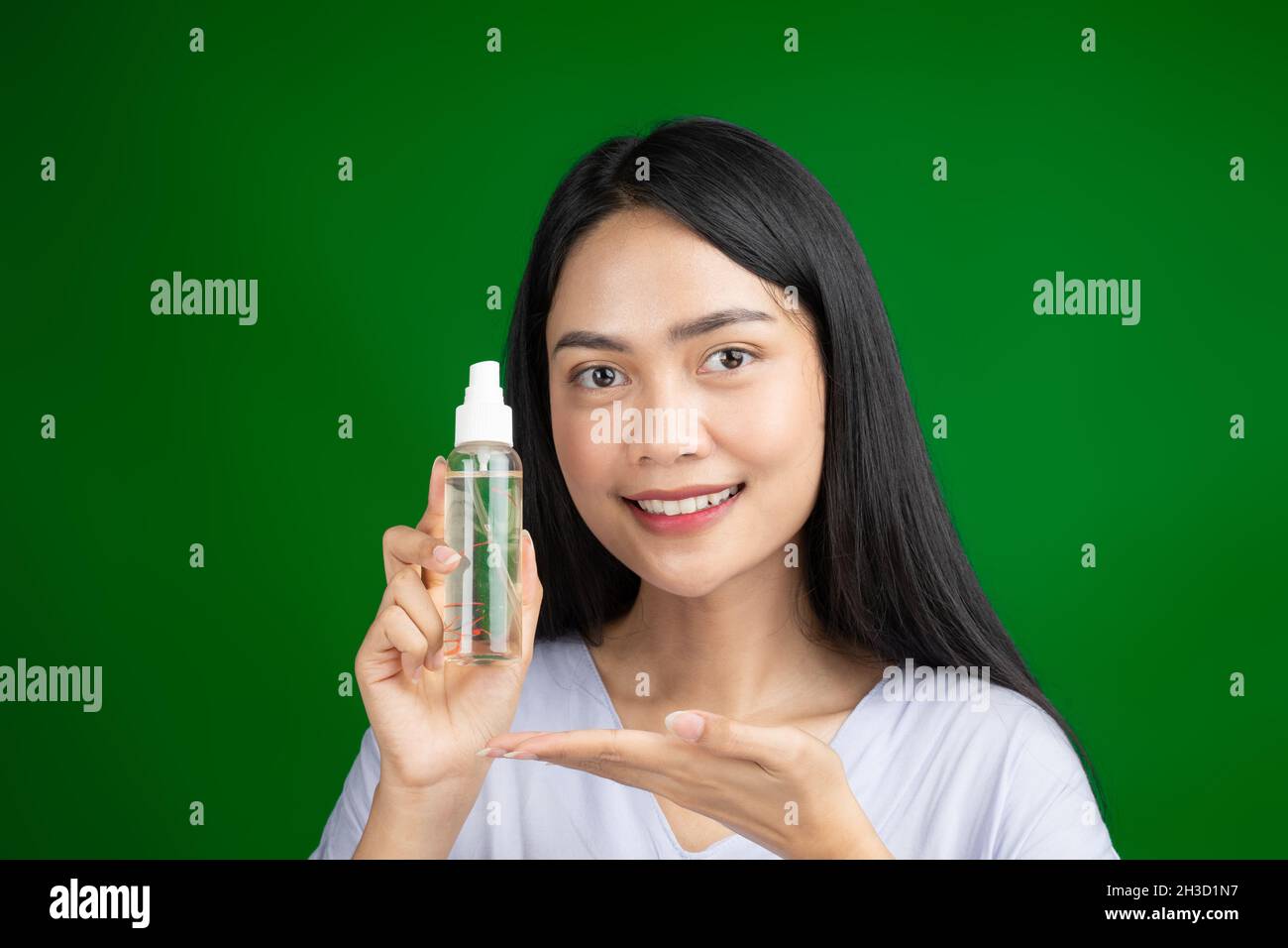 beautiful woman holding serum spray bottle on green screen Stock Photo