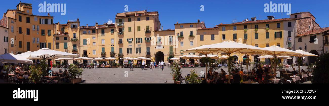 Panorama of yellow buildings and outdoor cafes in Piazza dell'Anfiteatro in town of Lucca, Tuscany, Italy Stock Photo