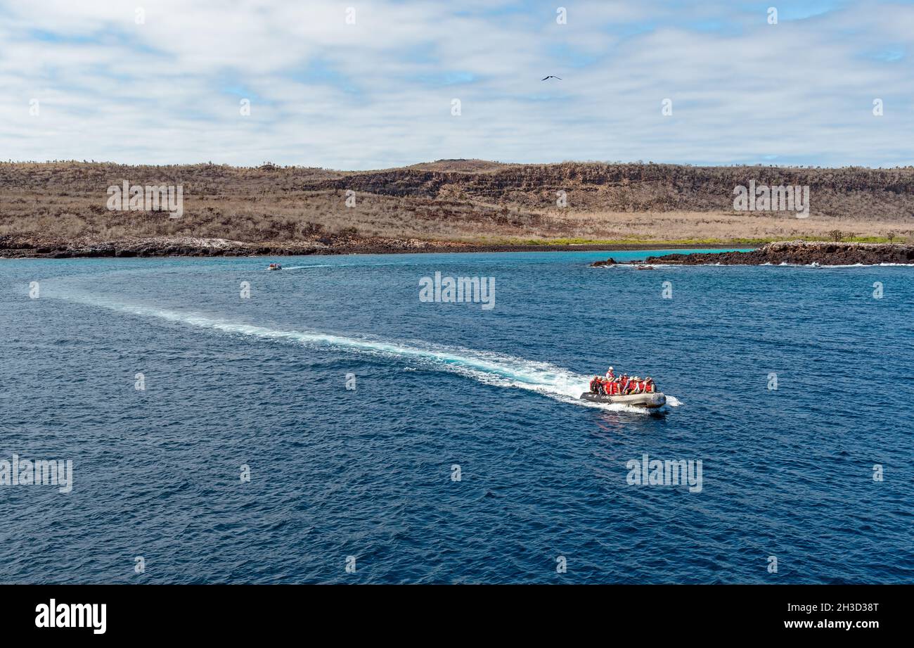Inflatable boat with tourists returning to cruise ship after snorkeling excursion by San Cristobal island, Galapagos national park, Ecuador. Stock Photo