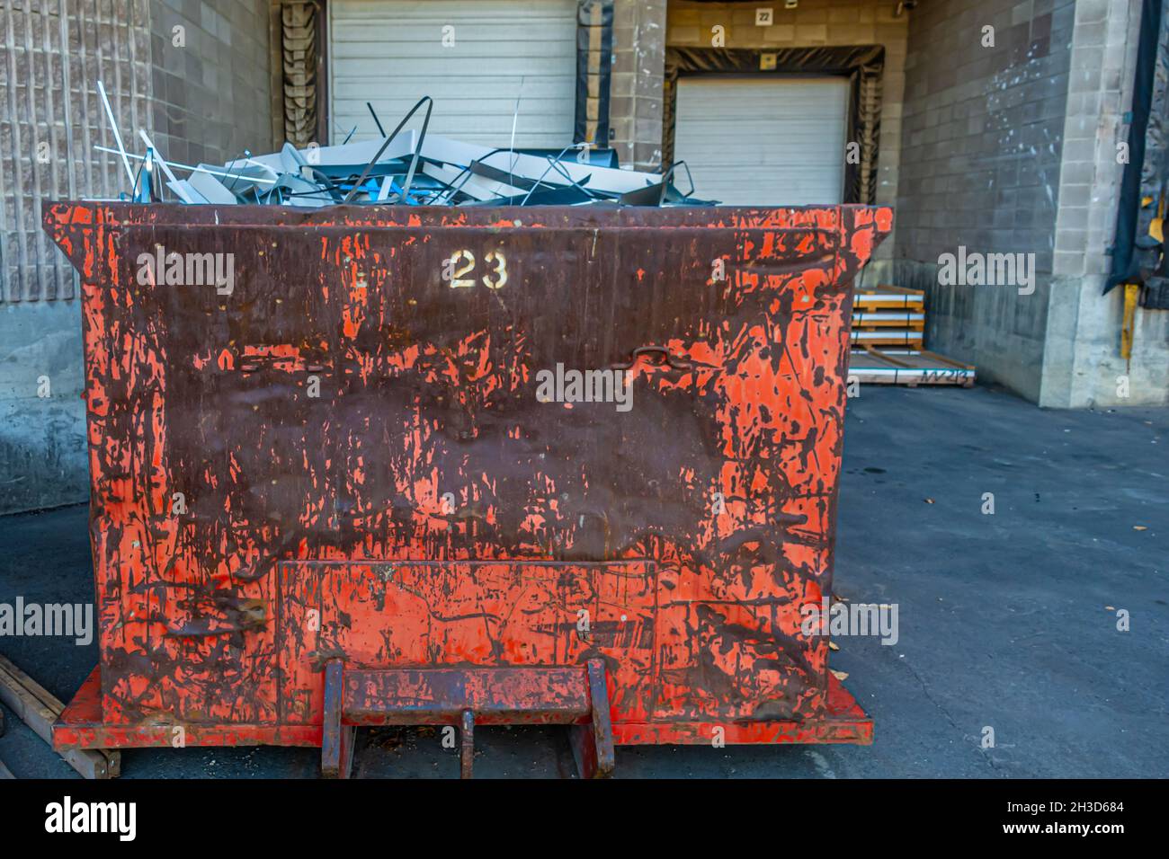 Garbage bin full of waste metal behind metal roofing factory Stock Photo